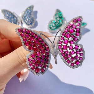 Macro detail of luxury silver butterfly brooch with red cubic zirconia and micro-pavé