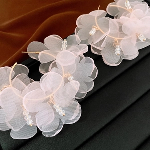 Detailed close-up of pink organza floral earrings with crystal bead and gold metal hardware