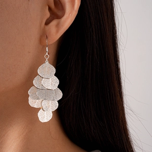 Detail of silver geometric leaf tassel earrings with hollow texture on female model