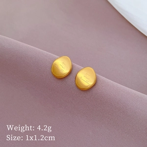 Gold oval titanium steel stud earrings with you are lovable engraving on purple fabric