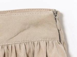 Détail de la fermeture éclair invisible et des plis sur la mini-jupe beige ballon