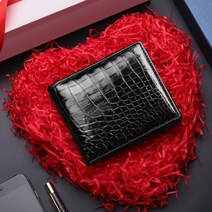 Short black crocodile embossed leather wallet for men on red heart-shaped gift background