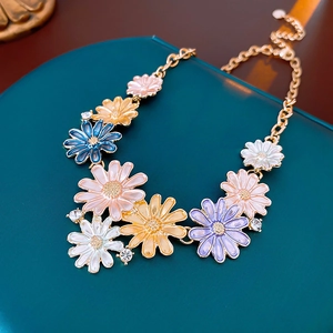 Close-up of colorful enamel daisy necklace with crystal accents on a golden chain