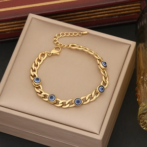 Gold-plated Cuban chain bracelet with blue evil eye charms on a jewelry box background