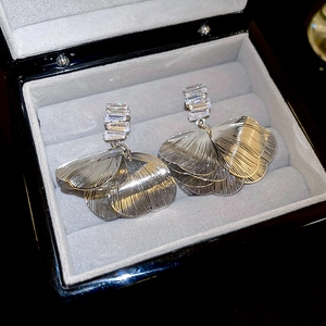 Macro detail of brushed metal flower petal earrings with zircon stones in a jewelry box