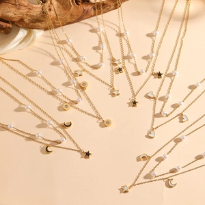 Detail view of double-layer gold necklaces with pearls, stars, moon and heart pendants