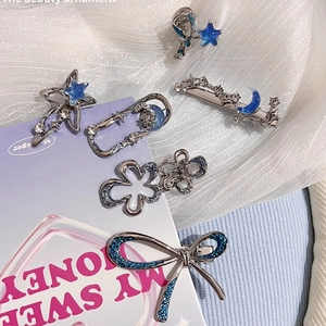 Detailed view of silver metal star and flower hair clips with blue decorative accents