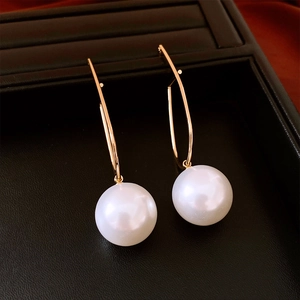 Detailed shot of long gold geometric bar earrings with large round white pearl pendants