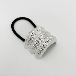 Close-up of silver wrinkled metal texture and black elastic hair tie on a grey background