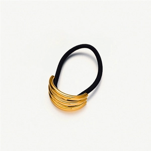 Detail of multi-layer gold stainless steel cuff on a black elastic hair tie for women