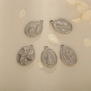 Religious silver stainless steel oval medallions set on beige textured fabric with petals