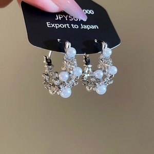 Detail of silver hoop earrings with white pearls and sparkling cubic zirconia stones