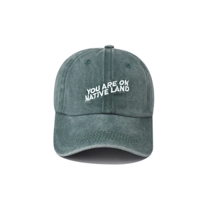 Detailed embroidery of 'YOU ARE ON NATIVE LAND' on washed cotton baseball cap