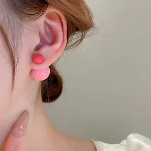 Close-up of dual-sided pink resin ball earrings worn to show the contrast design