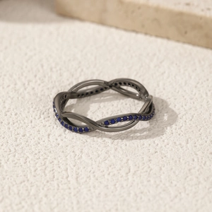 S925 sterling silver black twisted ring with pavé blue round stones on stone surface