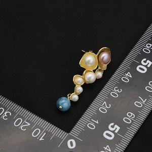 Natural pearl earrings with blue gemstone drops and gold hardware on black background