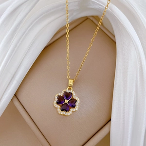 Close-up of golden clover necklace with purple heart stones and sparkling crystals
