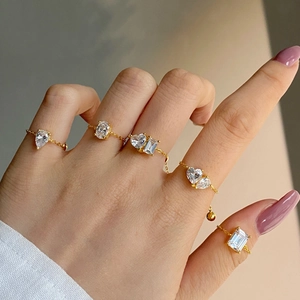 Close-up of adjustable gold chain rings featuring teardrop and oval zircon stones