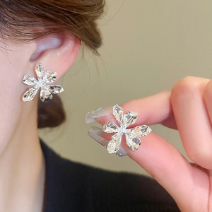 Macro detail of textured silver floral earrings with organic petal design on model