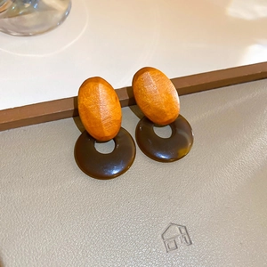 Detail of geometric wood and resin earrings showing natural texture and amber finish