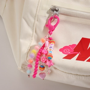 Vue macro détaillée du porte-clés rose avec perles LOVE et pendentifs étoiles sur un sac à dos