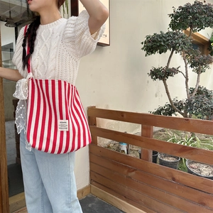 Detail of red and white striped canvas tote bag with white lace ribbon and brand logo tag