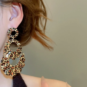 Close-up of tiered leopard print hoop earrings on model with wavy texture detail