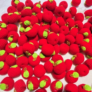 Close-up of bulk handmade crochet red apples with green leaves and brown stems