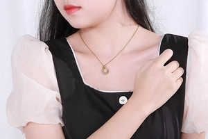 Detail of a gold water-drop hollow pendant with sparkling rhinestones on a thin chain