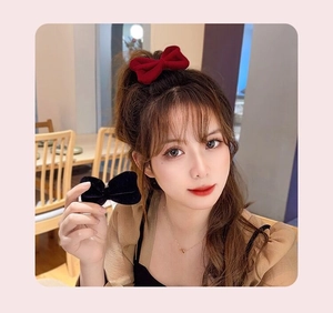 Detail of elegant velvet bow hair clips in red and black colors worn by a model