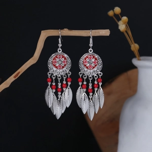 Detail of bohemian silver earrings with red enamel flowers and feather pendants