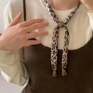 Detail view of leopard print silk scarf necklace with brown round beads on neck