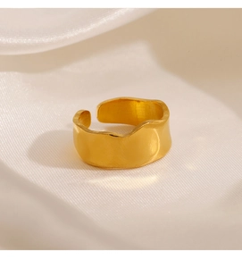 Macro shot of gold wide wavy open ring with irregular lava texture on white silk fabric
