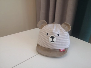 Detail of striped baby sun hat featuring bear ears and cute cartoon animal patch