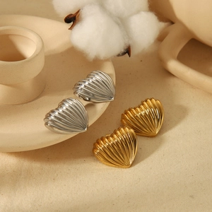 Elegant 18k gold and silver heart earrings with vertical striped texture on ceramic tray