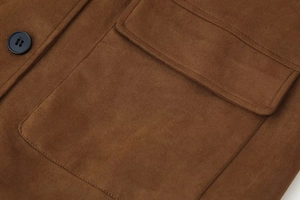 Detail of brown suede jacket showing worker-style flap pocket and black button