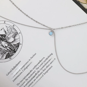 Macro view of blue opal pendant on silver chain necklace over vintage paper