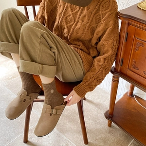 Detail showing deep brown ribbed socks with floral embroidery and suede mule shoes