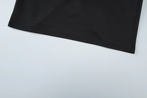 Detailed close-up of double-stitched hem and fabric texture of black mesh slit dress