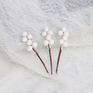 Close-up of three artificial pearl white berry stems on a soft white plush background