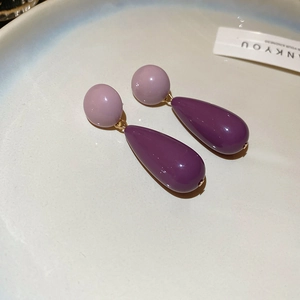 Close-up of vintage acrylic teardrop earrings in two-tone purple on a ceramic tray