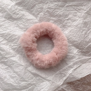 Close-up of soft pink faux rabbit fur scrunchie showing fluffy texture on white paper