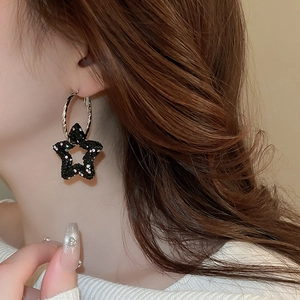 Detail of silver hoop earring with black star pendant encrusted with sparkling crystals
