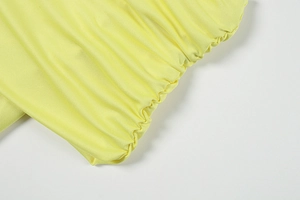 Détail rapproché du tissu en maille jaune citron avec fronces élastiques et coutures fines