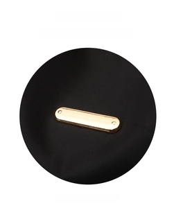 Detail of high-density black nylon fabric and polished gold metal buckle on backpack
