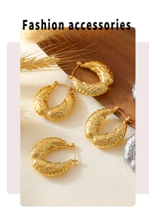 Detail of wing-shaped gold and silver earrings with vintage feather texture on wood