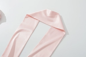 Vue détaillée d'une écharpe en satin rose clair avec texture de soie lisse sur blanc
