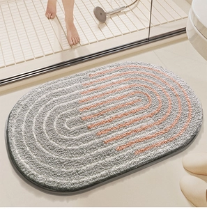 Thick plush oval bathroom mat with gray base and orange stripes in modern shower setting