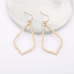 Close-up of beige teardrop earrings with textured hollow design on marble display