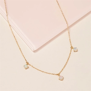 Close-up of gold chain necklace featuring three round opal pendants with prong settings